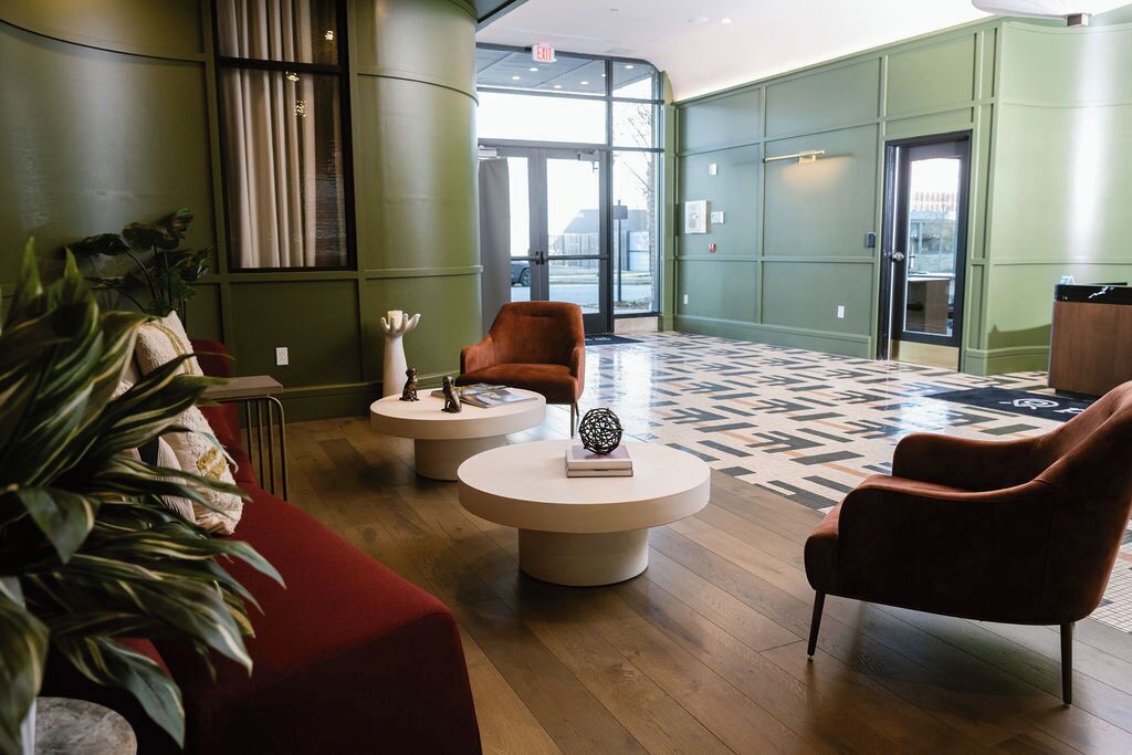 A lobby with a red sofa, two round tables, and a large patterned rug.