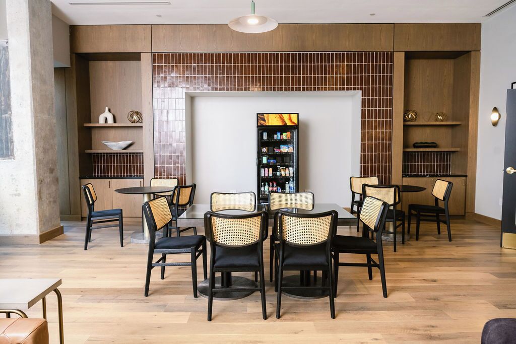 A modern interior with a central dining area, surrounded by shelves and a television.