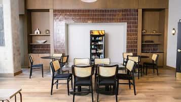 A modern interior with a central dining area, surrounded by shelves and a television.
