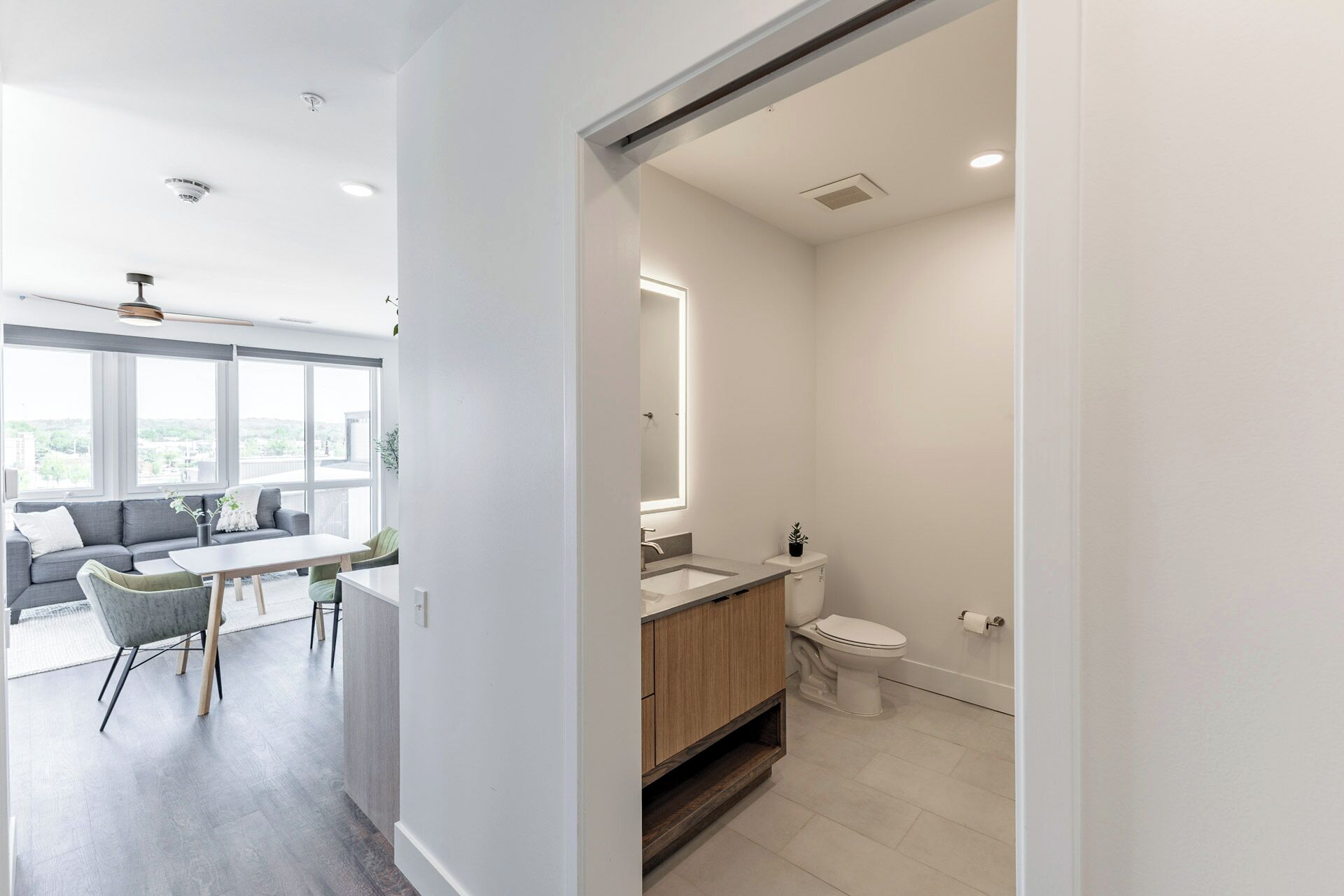 A modern apartment with a dining area, a bathroom, and a view of the city.
