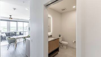 A modern apartment with a dining area, a bathroom, and a view of the city.