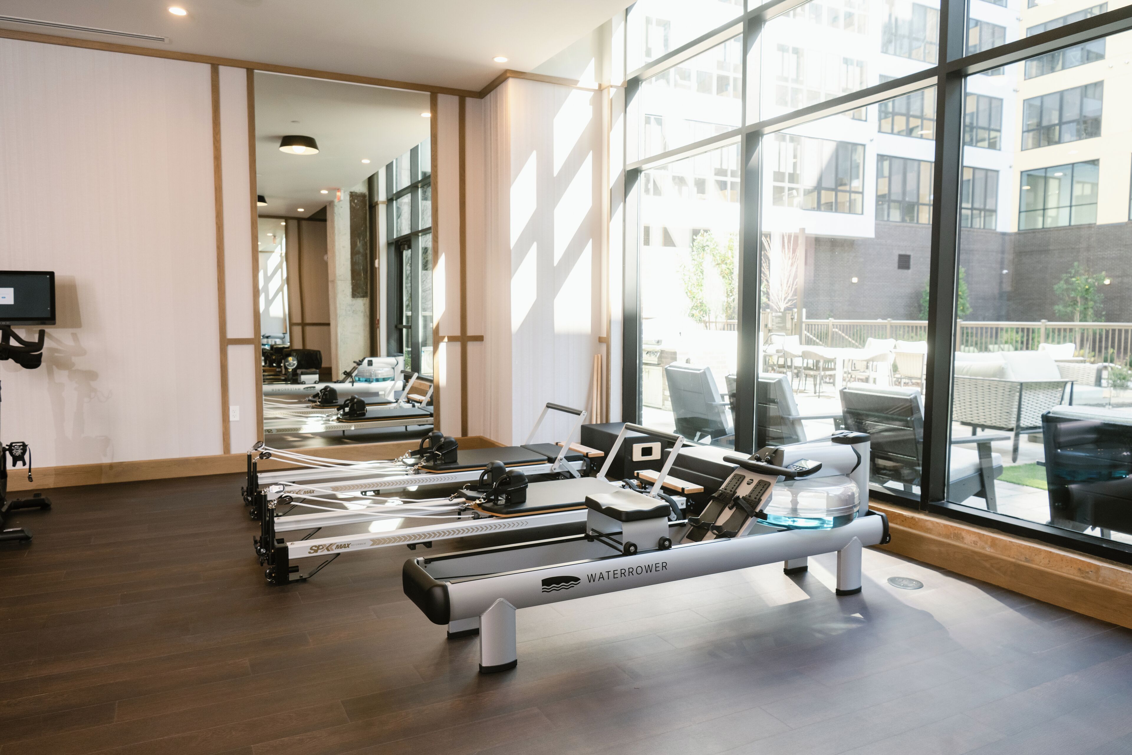 Ein Fitnessraum mit Rudergeräten, Laufbändern und einer Spiegelwand.