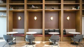 A modern seating area with wooden paneling, round tables, and grey chairs.