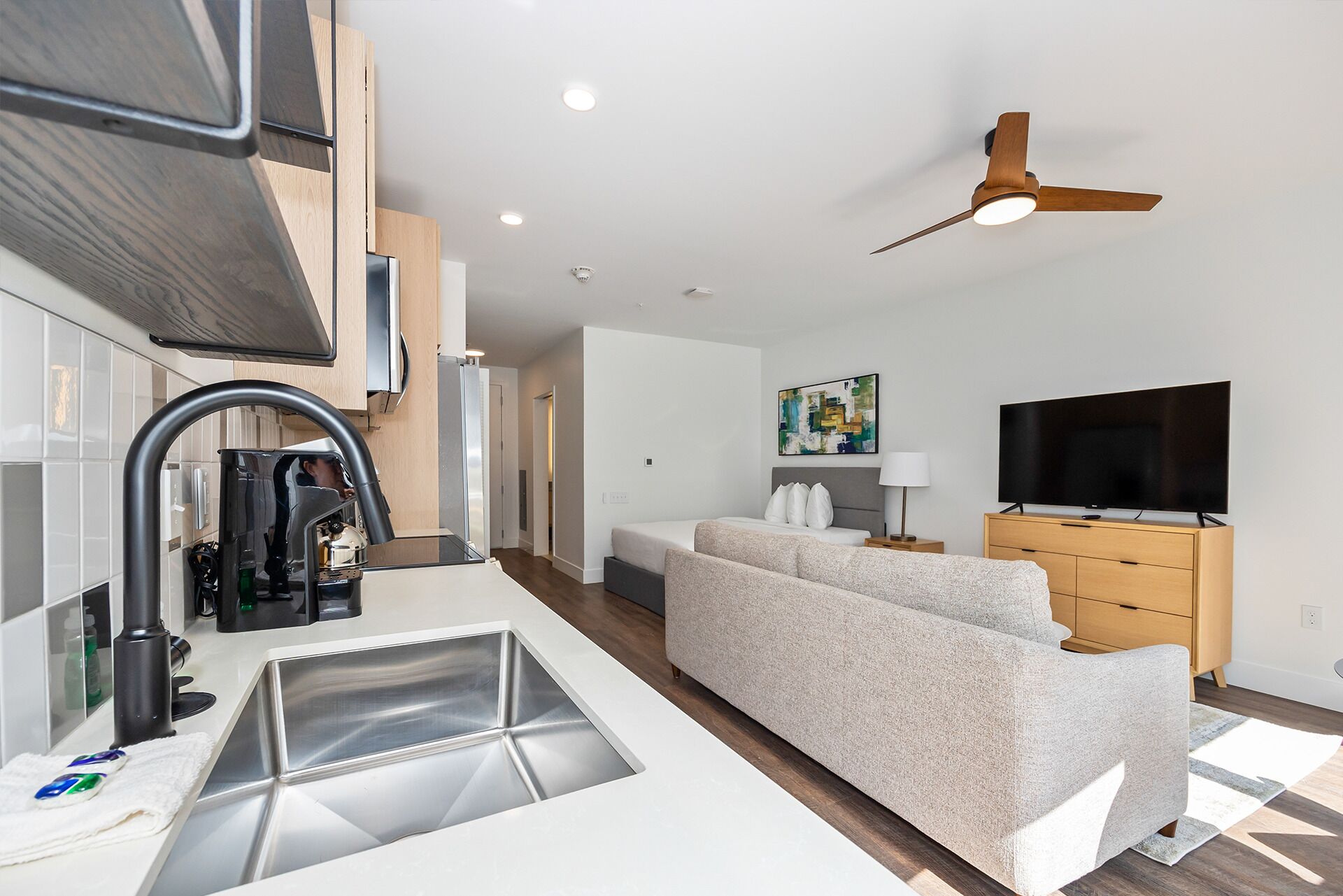 A modern kitchen with a built-in dishwasher, a large window, and a ceiling fan.