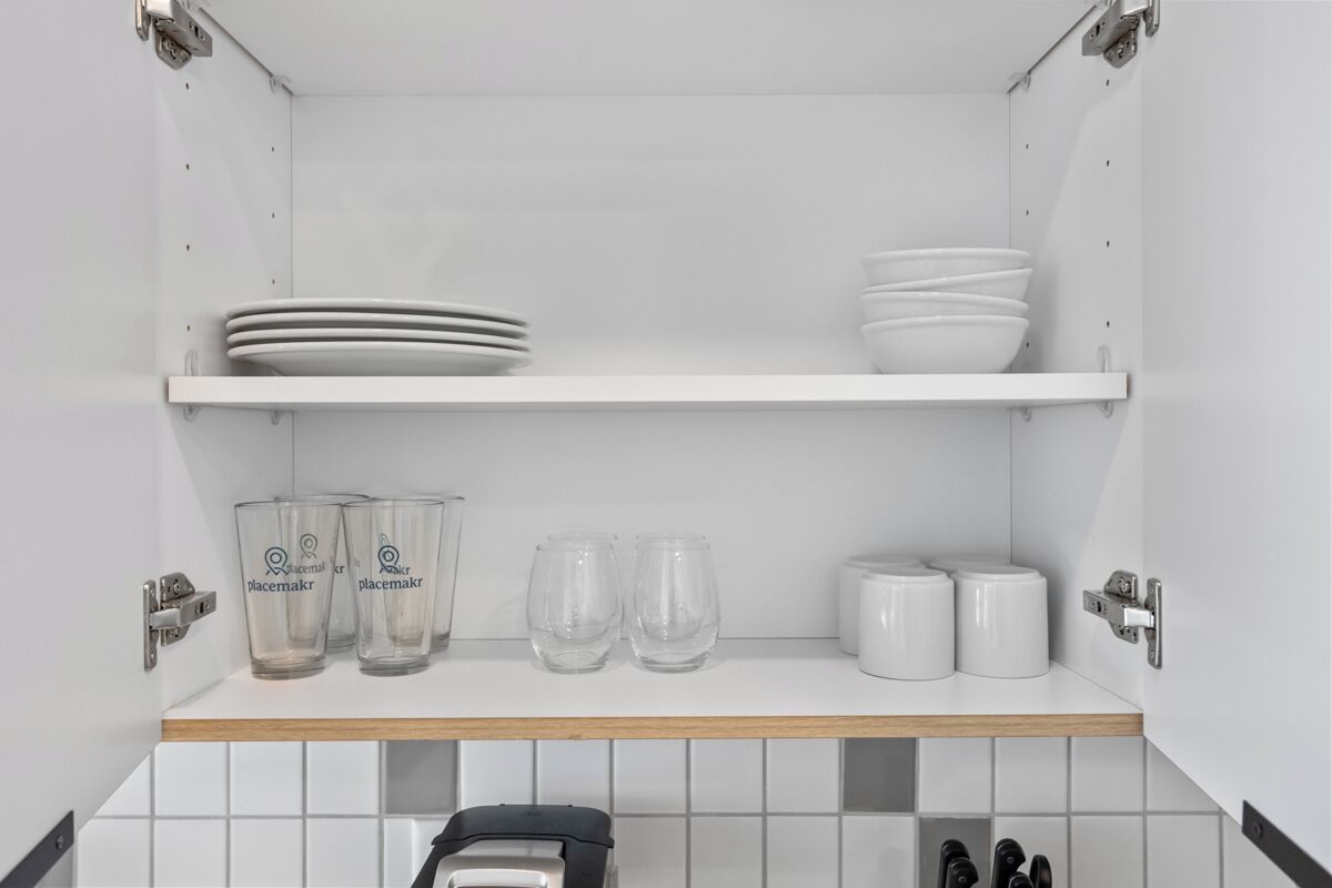 A kitchen with white cabinets, a white countertop, and a black appliance.