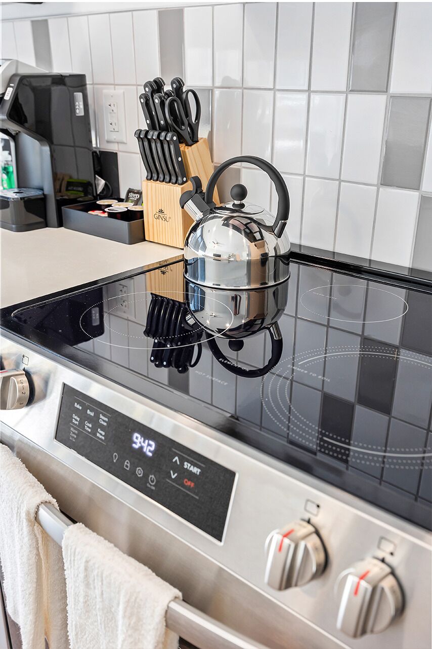 Una cocina moderna con estufa de acero inoxidable, hervidor y bloque de cuchillos.
