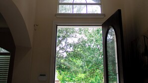 Una habitación con un amplio ventanal arqueado, una lámpara colgante y una puerta que da al exterior.