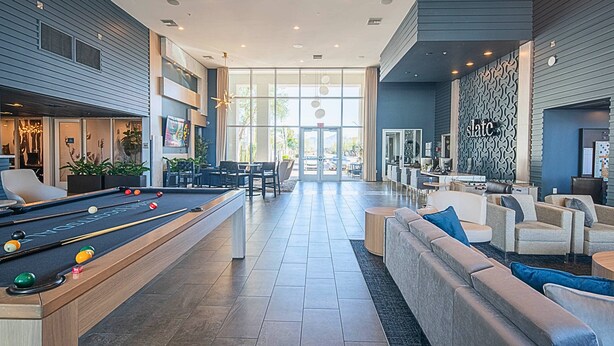 A modern indoor pool area with a pool table, comfortable seating, and a large window offering a view of the outdoors. - Near Mayo Clinic | King Bed | Heated Pool (Phoenix)