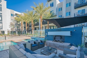 Zona junto a la piscina con mobiliario exterior y una chimenea moderna.