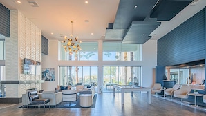 A spacious lobby with a pool table, comfortable seating, a modern chandelier, and large windows offering views of palm trees. - Near Mayo Clinic | King Bed | Heated Pool (Phoenix)