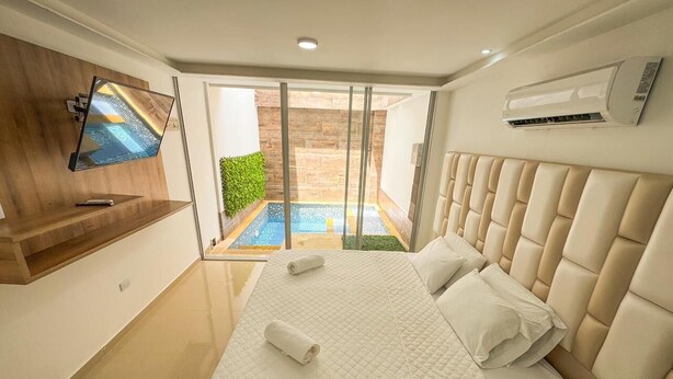 Un dormitorio moderno con una cama grande, un televisor montado en la pared y un equipo de aire acondicionado.