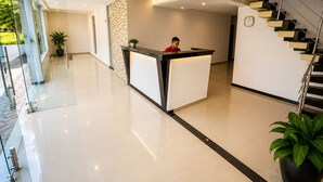 Un área de recepción moderna con una recepcionista, una escalera y un muro de cristal.