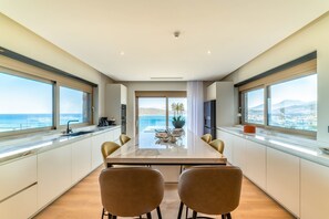A modern kitchen with large windows, a marble countertop, and a dining area with two chairs.