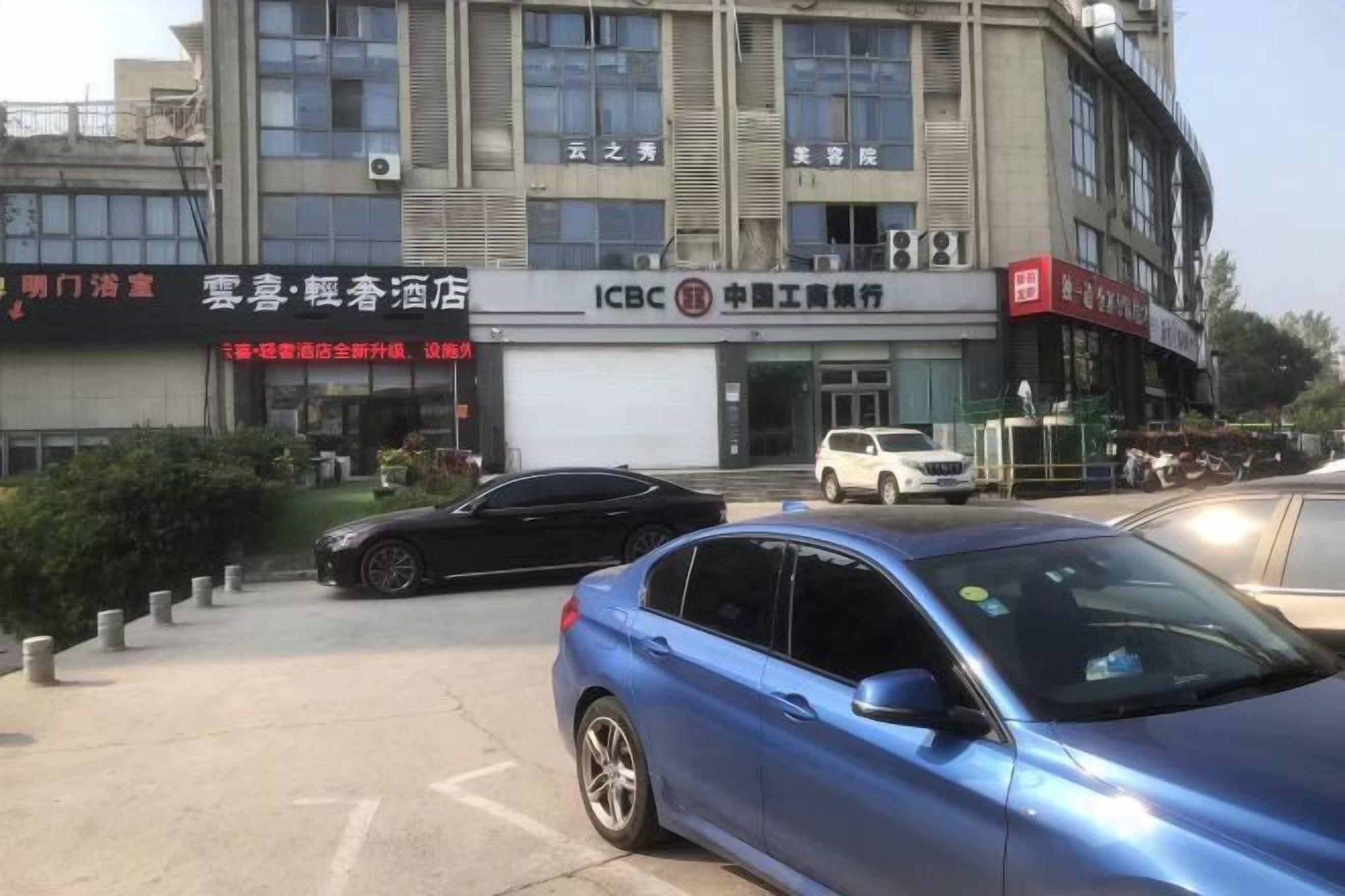 Un edificio con un letrero de ICBC y otro letrero de hotel. Hay coches estacionados en la parte delantera.