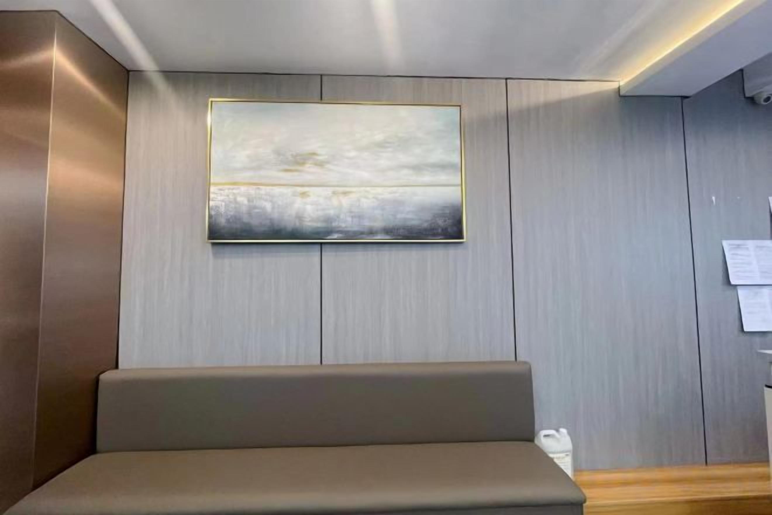 Een receptiezone met een bank, een wanddecoratie en een houten bureau.