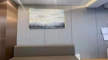 Een receptiezone met een bank, een wanddecoratie en een houten bureau.
