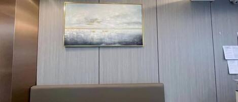 Un área de recepción con un banco, un cuadro en la pared y un escritorio de madera.