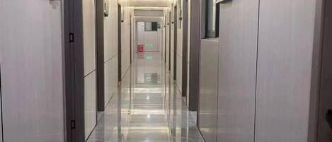A long, narrow hallway with doors on both sides, leading to individual rooms.