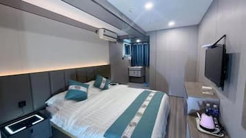 A modern hotel room with a large bed, bedside tables, a TV, and a bathroom with a mirror and sink.