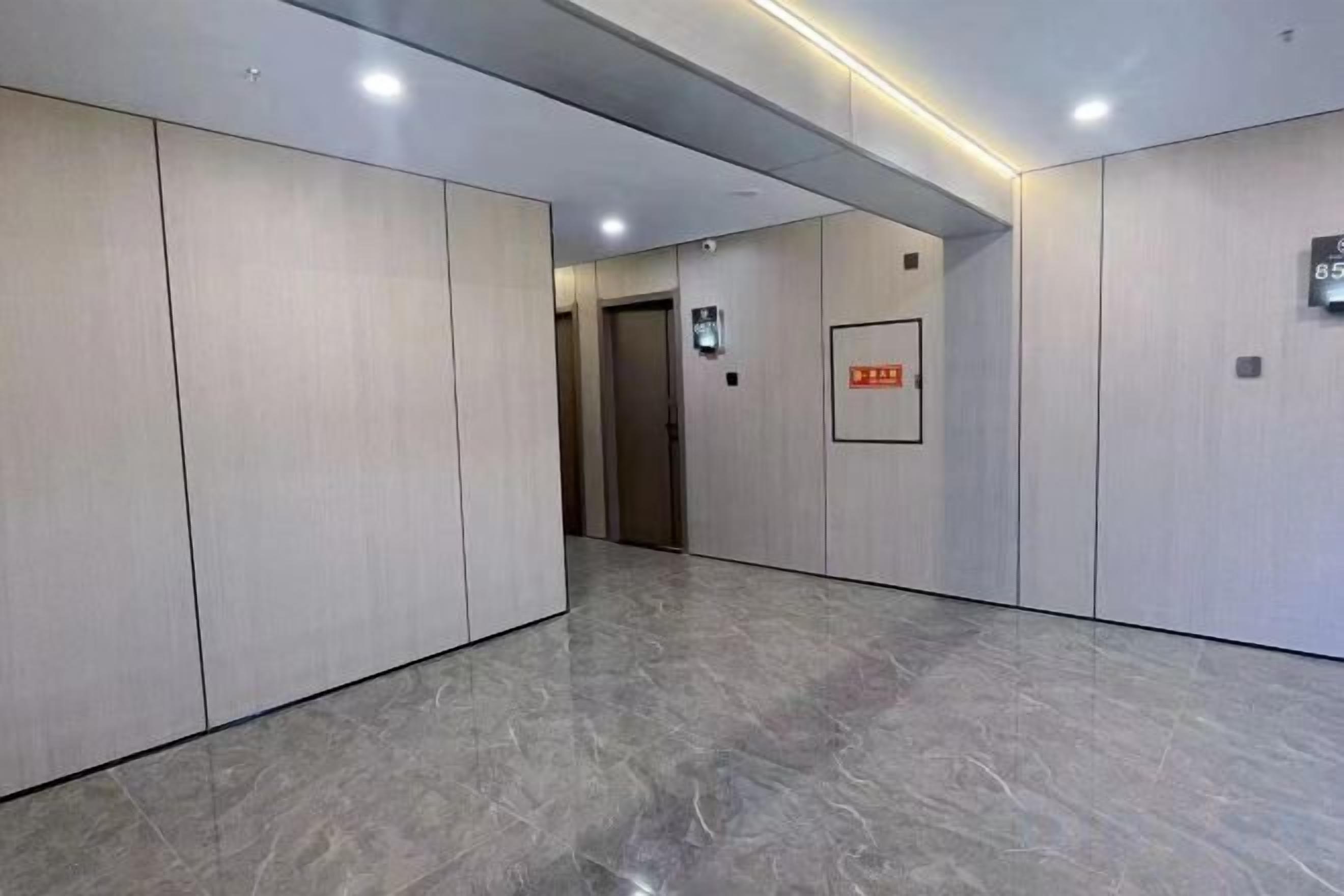 A hallway with a marble floor, light-colored walls, and a door at the end.