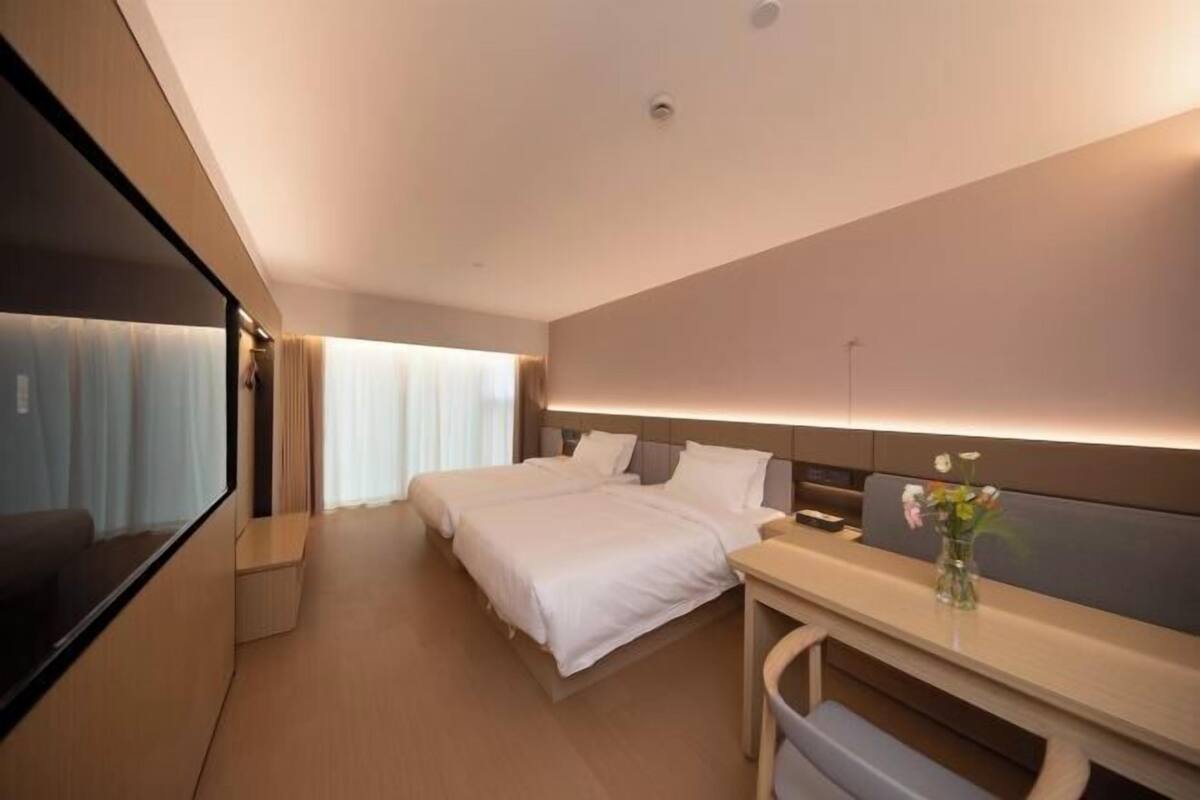 A modern hotel room with a large bed, a desk, and a flat-screen TV.