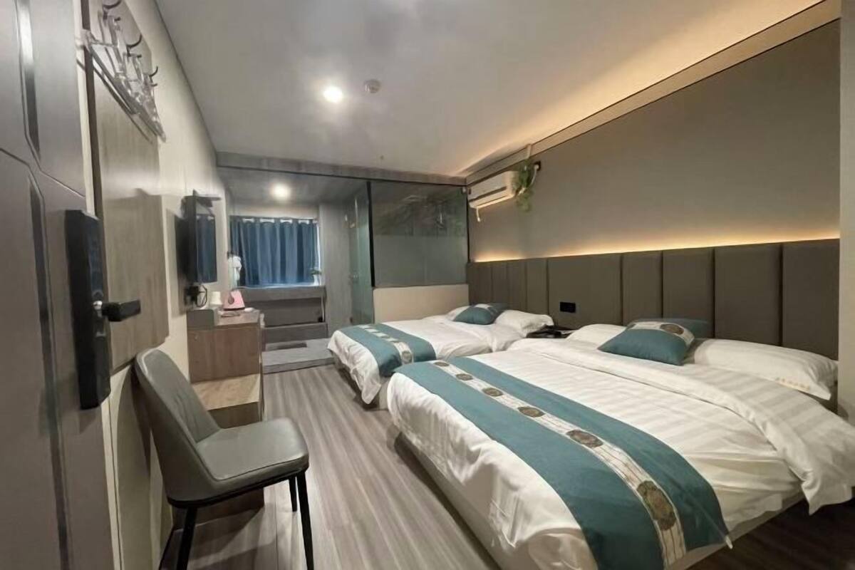 A hotel room with two beds, a desk, a chair, and a large mirror.