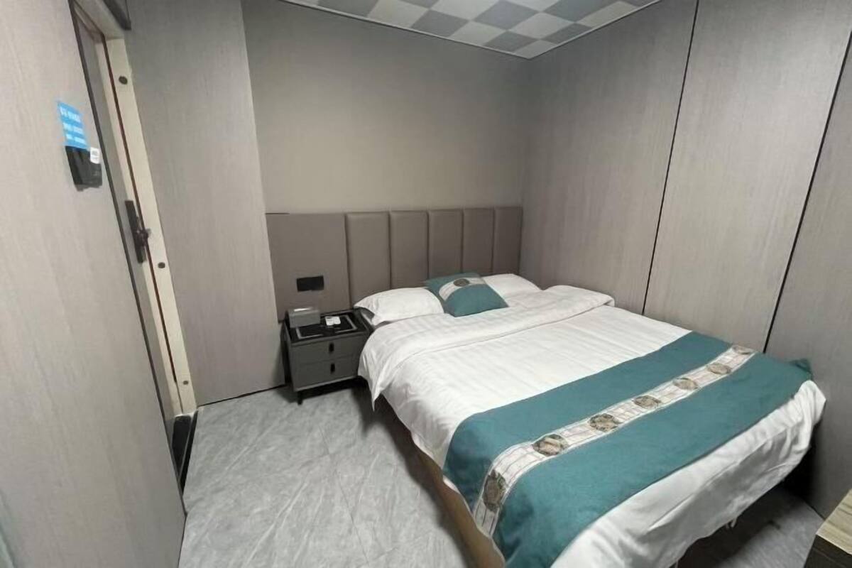 A hotel room with a bed, a nightstand, and a wall-mounted phone.