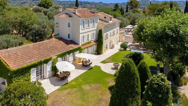 Un'ampia casa a due piani con tetto in tegole, piscina e giardino curato.