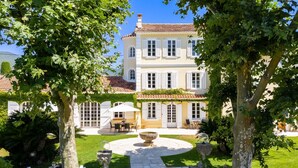 Un edificio grande su due piani, con tetto in tegole, immerso nel verde e circondato da un giardino curato.