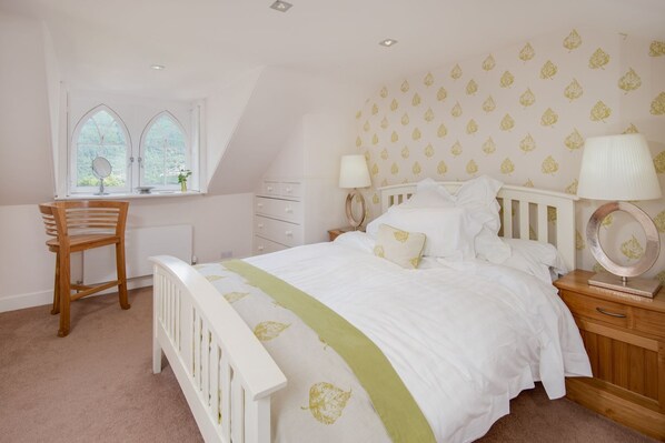 A bedroom with a bed, a desk, a chair, and a window with a view.