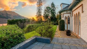 Un jardín ajardinado con un sendero de piedra que conduce a un edificio con ventanas arqueadas.