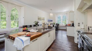 Una cocina amplia con una isla grande, encimeras de madera y vistas al exterior a través de amplios ventanales.