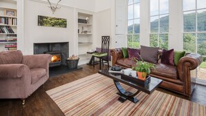 Un amplio salón con chimenea, sofás de cuero, una mesa de centro y una estantería.