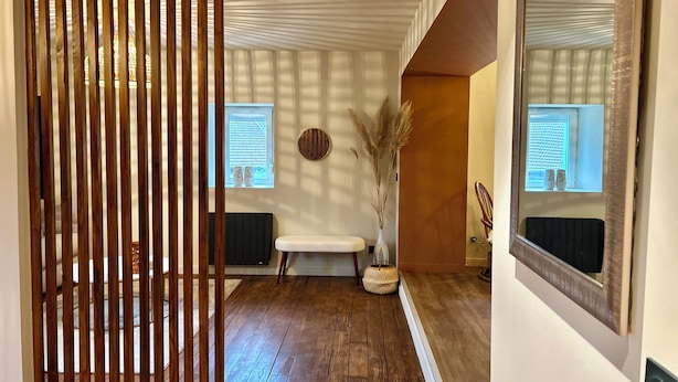 A hallway with a wooden partition, a bench, a vase with dried plants, and a mirror on the wall. - Ferme Gabriela | Luxury accommodation in the lake region in the heart of the Jura mountains (Châtillon)