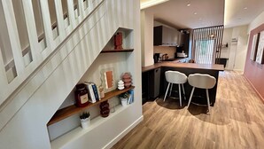 A modern kitchen with a wooden countertop, two white bar stools, and a built-in oven. - Ferme Gabriela | Luxury accommodation in the lake region in the heart of the Jura mountains (Châtillon)
