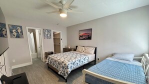 A bedroom with two beds, a ceiling fan, a wardrobe, and a painting on the wall. - Cozy 1-bed apt in fabulous Pompano Beach across from the beach, AC, WiFi, pets (Pompano Beach)