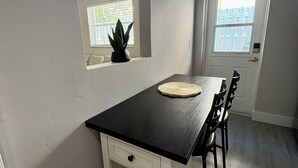 A compact kitchen with a black countertop, a small window with a plant, and a door leading outside. - Cozy 1-bed apt in fabulous Pompano Beach across from the beach, AC, WiFi, pets (Pompano Beach)