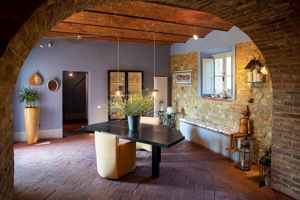 A cozy dining area with a black table, cushioned chairs, and a hanging light fixture. - Villa Majolica - Five Bedroom Villa, Sleeps 11 (Montelupo Fiorentino)