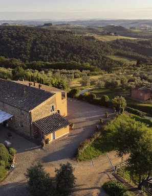 A rural property with a large stone building, a gravel driveway, and surrounding greenery.