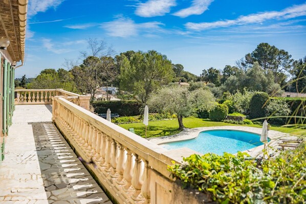 A swimming pool with a stone deck, surrounded by greenery and trees.