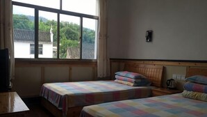Une chambre avec deux lits, une tête de lit en bois, une fenêtre et une vue sur la verdure.