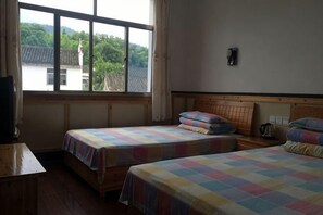 A room with two beds, a wooden headboard, a window, and a view of greenery outside. - Xiangshuiju Inn (Jing County)