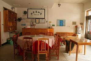 Un coin repas comprenant une table ronde, des chaises, un buffet en bois et un radiateur.