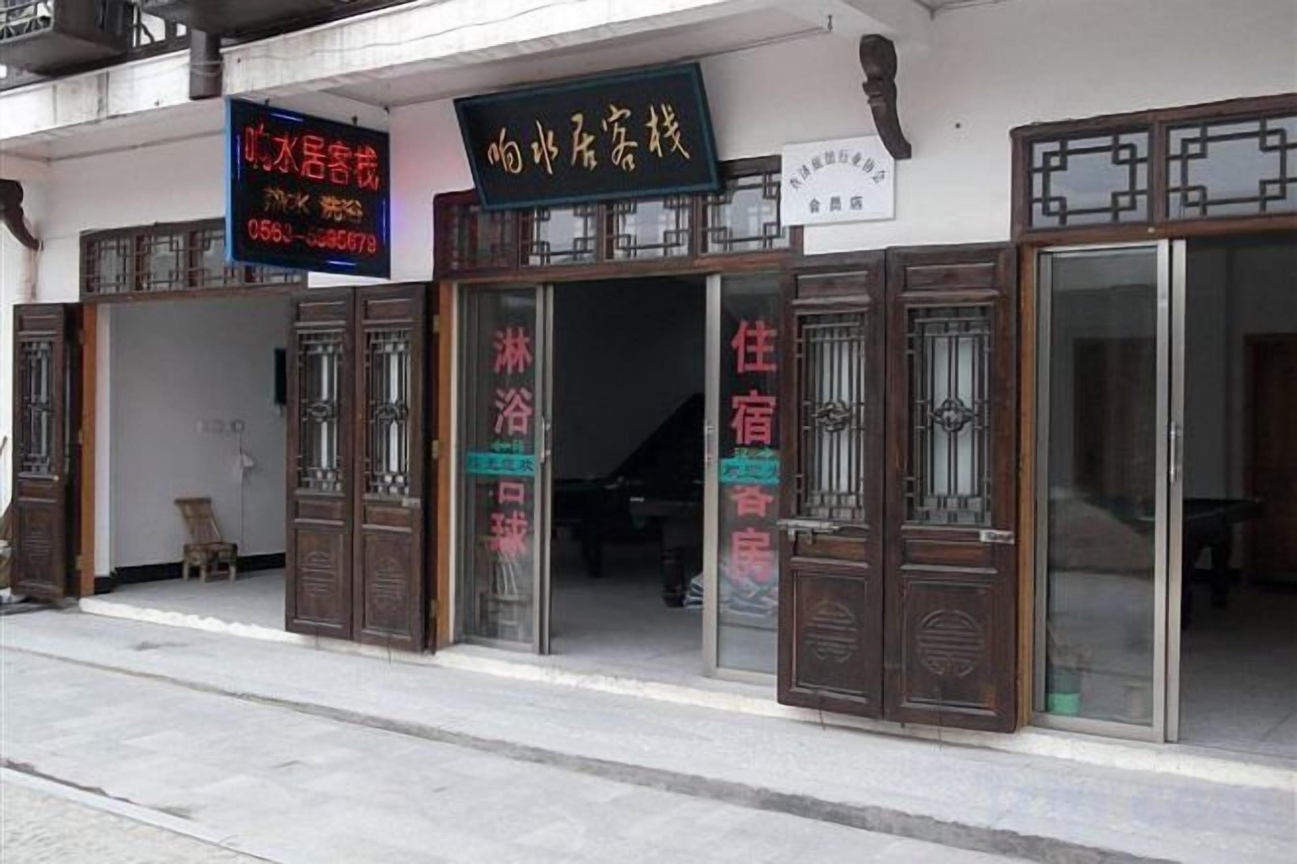 A traditional Chinese building with wooden doors and signage indicating a hotel and a restaurant.