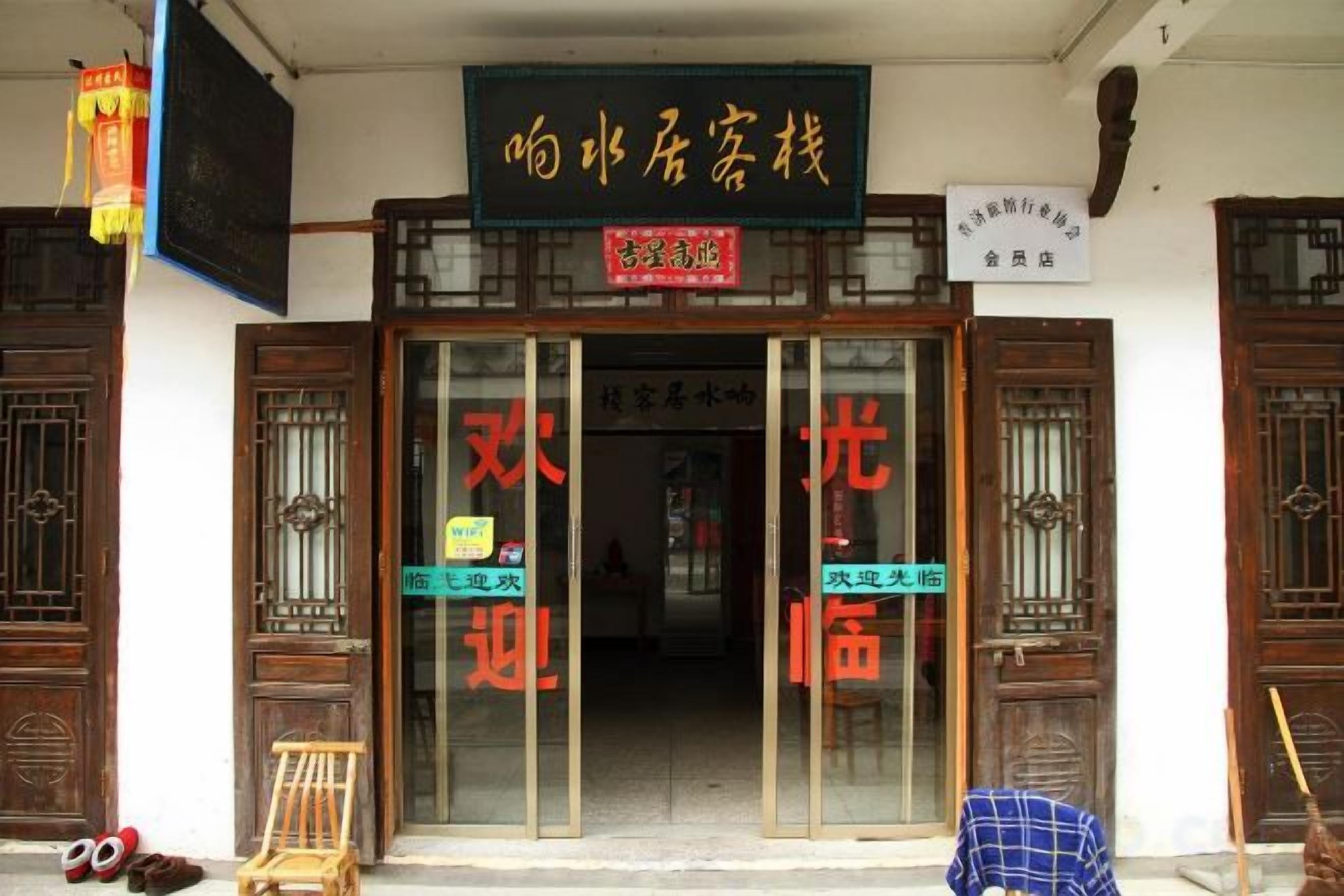 A traditional Chinese building with a signboard, wooden doors, and a small stool outside.
