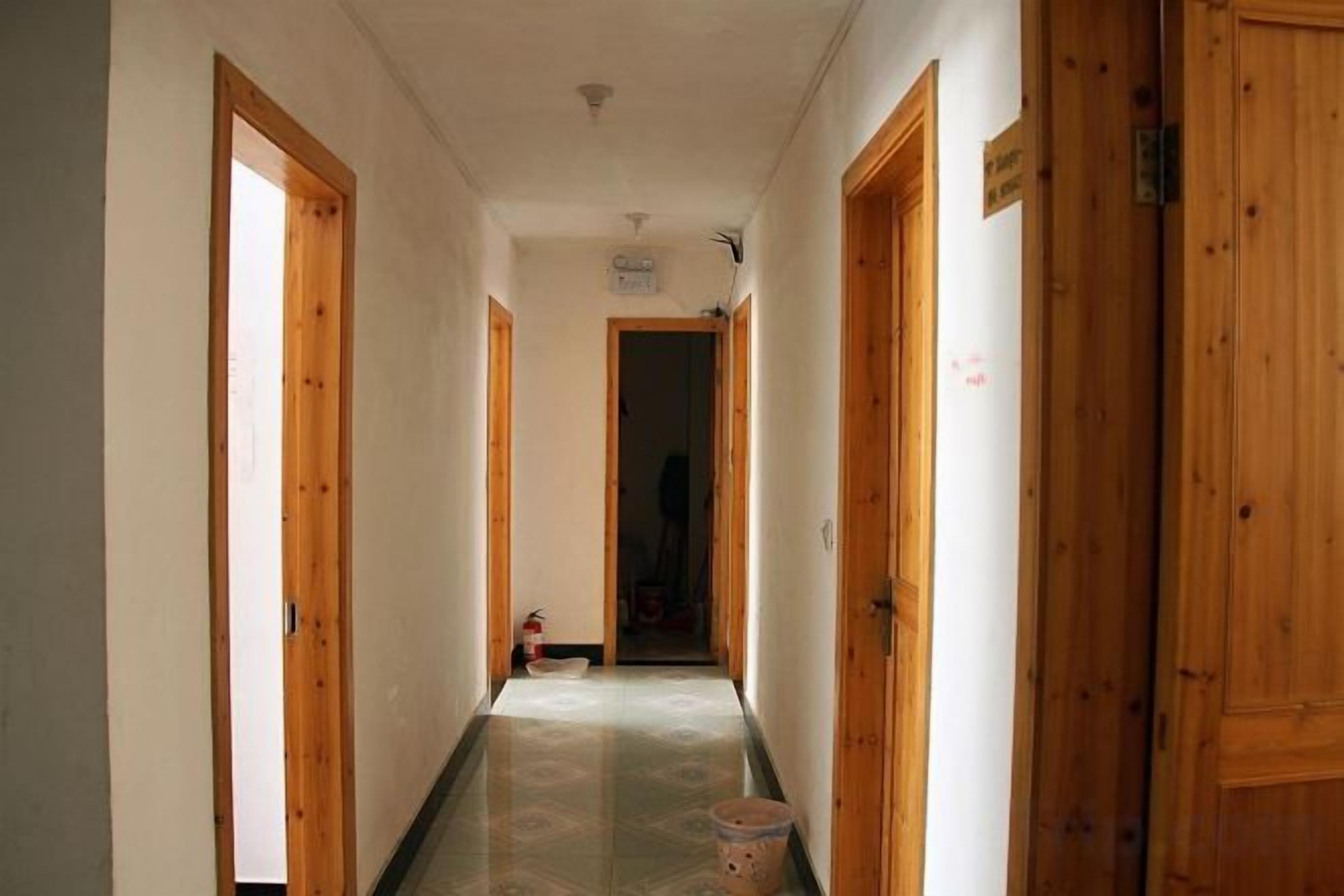 Un pasillo con puertas de madera y piso de baldosas.
