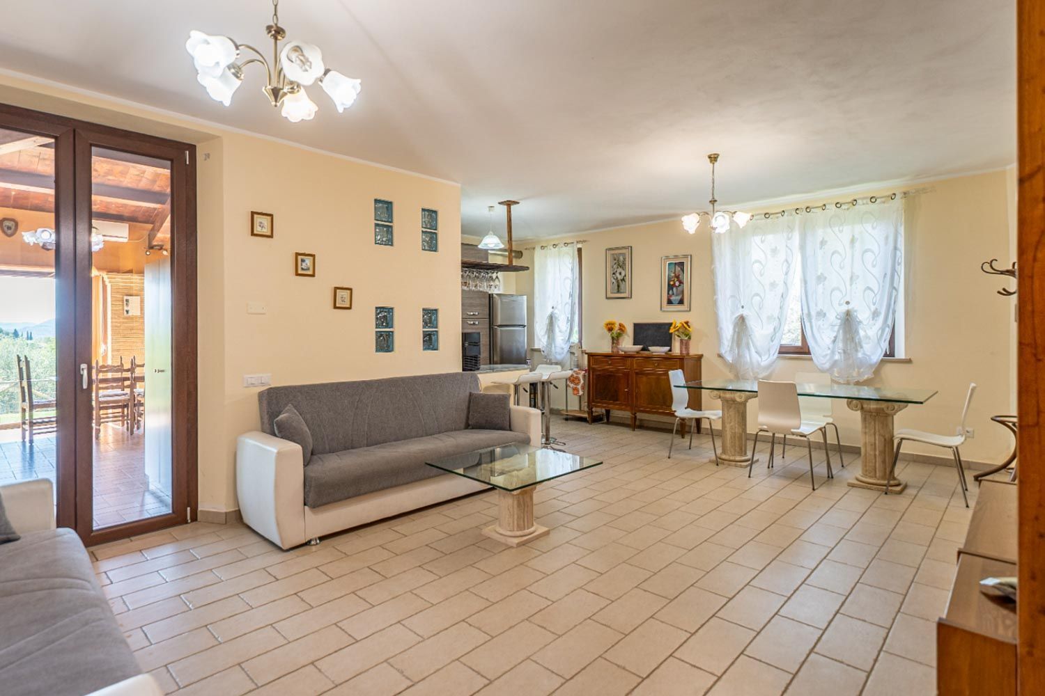 Un salon avec un canapé, une table basse, une table à manger, des chaises et, au fond, une cuisine.