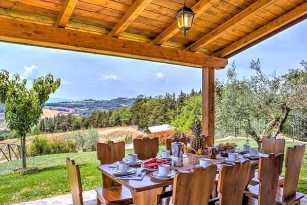 A wooden outdoor dining area with a table set for two, overlooking a scenic landscape.