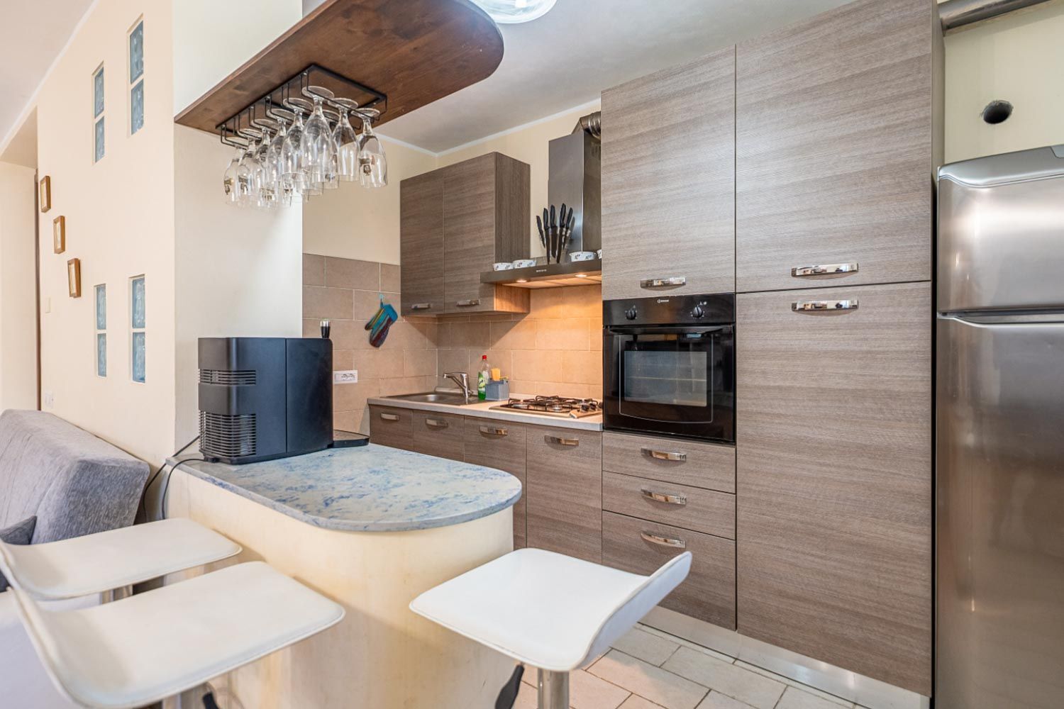 A modern kitchen with a built-in oven, a coffee machine, and a wine rack.