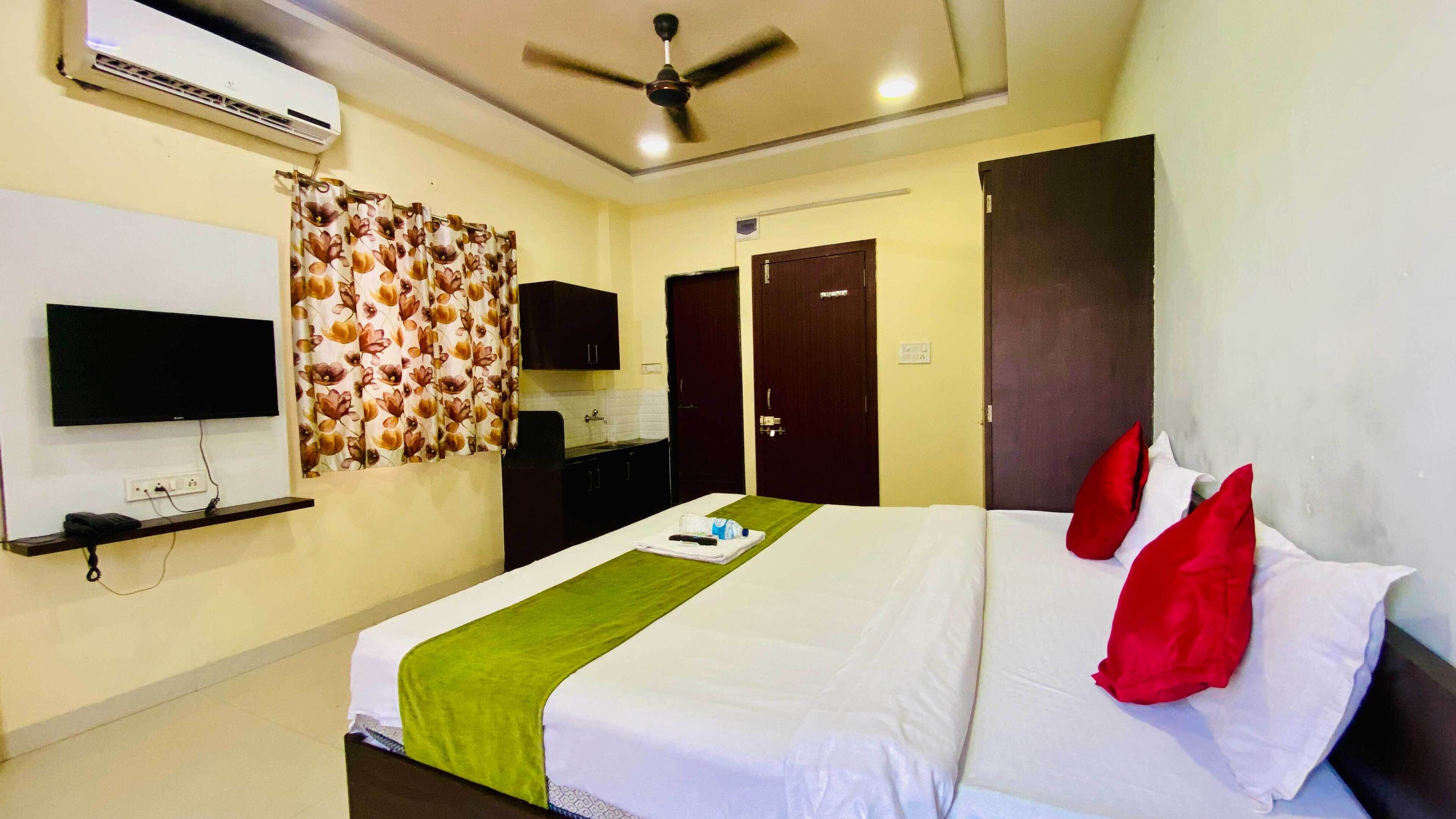 A hotel room with a bed, a television, a wardrobe, and a ceiling fan.